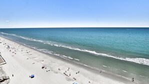 A beach with a clear sky, calm sea, and people relaxing on the sand. - Oceanfront 1bed/2bath-Water's Edge Resort-1405 Indoor/Outdoor Pool & Hot Tub (Garden City Beach)
