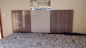 A bedroom with a bed, a headboard, and a wall-mounted sign. - Rua Maria Tognini 450 (Praia Grande)