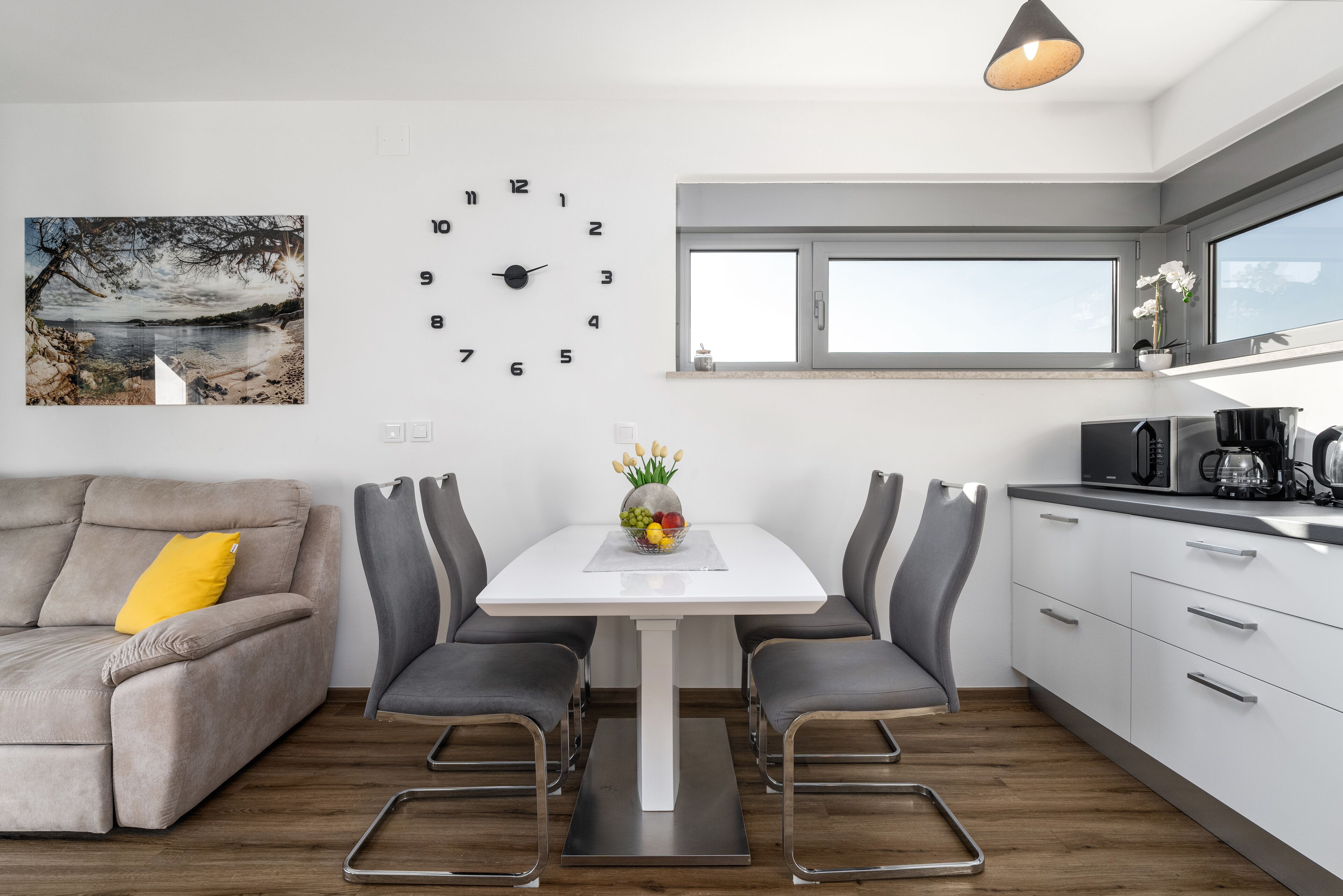 Une cuisine moderne avec une table à manger, des chaises et une horloge au mur.