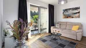 A living room with a sofa, a glass door leading to a balcony, a dining table, and a vase with plants. - Modern apartment directly at the marina Vrsar and 300m from the beach (Vrsar)
