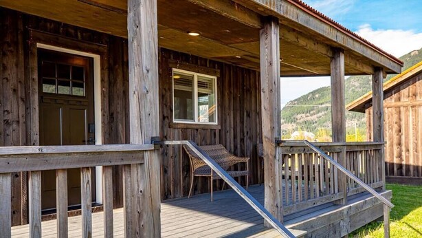 A wooden cabin with a porch, a door, and a window.