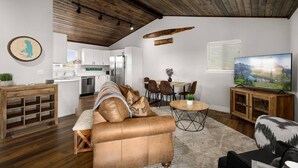 A modern living room with a leather sofa, wooden coffee table, and a flat-screen TV.