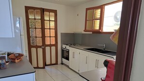 Une cuisine avec des meubles blancs, une cuisinière, un évier et un réfrigérateur.