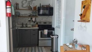 A compact kitchen with a microwave, oven, and refrigerator. There is a small dining area with a table and chairs. - Rustic Private Studio  (Toa Baja)