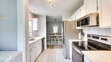 A modern kitchen with white cabinets, stainless steel appliances, and patterned flooring.