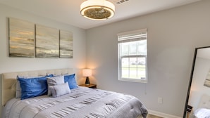 Et soveværelse med en stor seng, et natbord, en lampe, et vindue og et spejl.