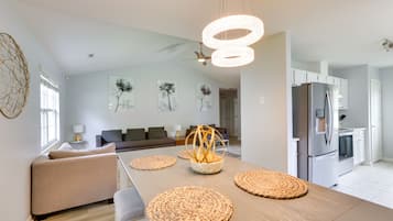 A modern kitchen with a central island, white cabinets, and a stainless steel refrigerator.