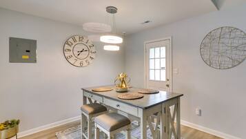 A dining area with a table, chairs, and a wall clock.