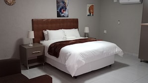 Habitación de hotel con una cama grande, dos mesitas de noche y una manta marrón.