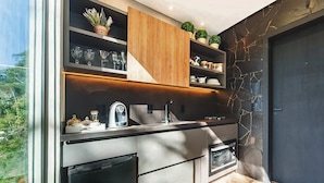 A modern kitchen with built-in appliances, a stone accent wall, and a view of greenery outside. - Rancho Carolina (Rancho Queimado)