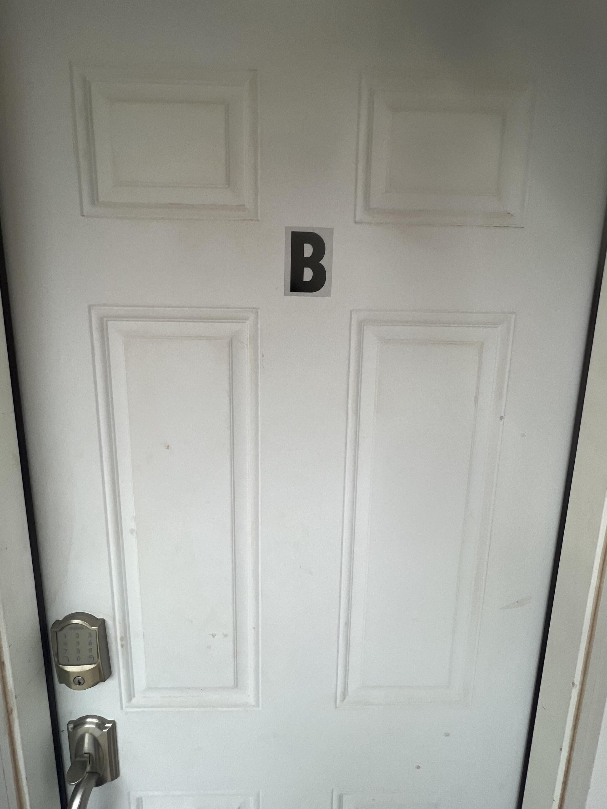 Una porta blanca amb rellotge numèric i un ull de cerradura.