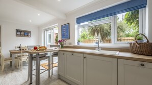 A modern kitchen with a large window, a dining area, and a view of the outdoors. - Miramare Cottage,  Holme-next-the-Sea, Norfolk (Holme-next-the-Sea)