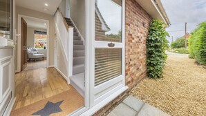 A modern house with a staircase leading to a second floor, a large sliding glass door, and a brick exterior wall. - Miramare Cottage,  Holme-next-the-Sea, Norfolk (Holme-next-the-Sea)