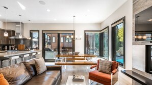 Una cocina moderna con una isla central, un comedor con mesa de madera y una zona de estar acogedora con sofá de cuero y una silla roja.