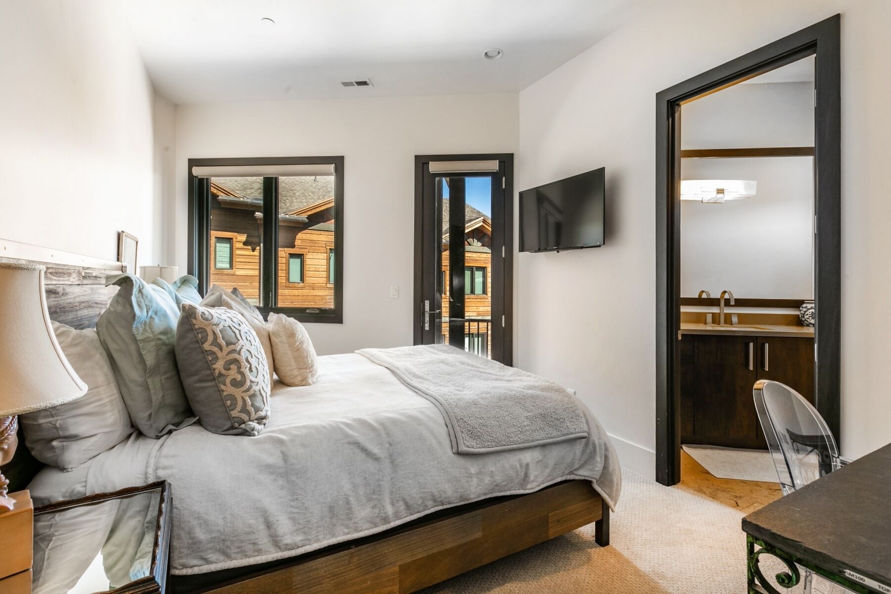 Une chambre à coucher avec un lit, une table de chevet, une lampe et un téléviseur fixé au mur.