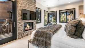 Una sala de estar moderna con chimenea, ventanas amplias y un sofá con almohadones de piel.