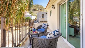 A balcony with wicker furniture, a table with drinks, and a view of a hillside. - Villa Cola de Ballena Luxury Villa with ARCADE Room, El Pedregal. Security 24/7 (Cabo San Lucas)
