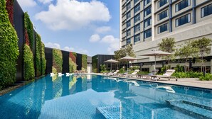 A modern hotel with a rooftop pool, lounge chairs, and a vertical garden.