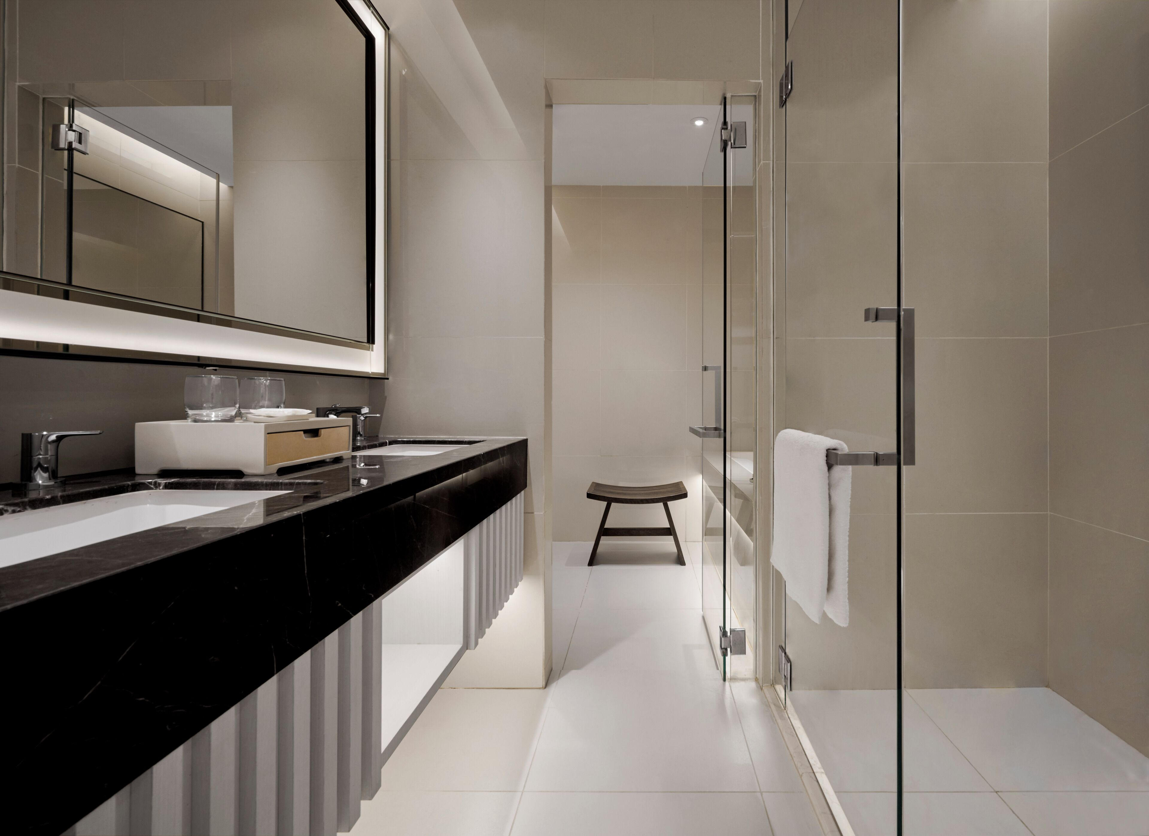 A modern bathroom with a black countertop, a large mirror, and a glass shower enclosure.