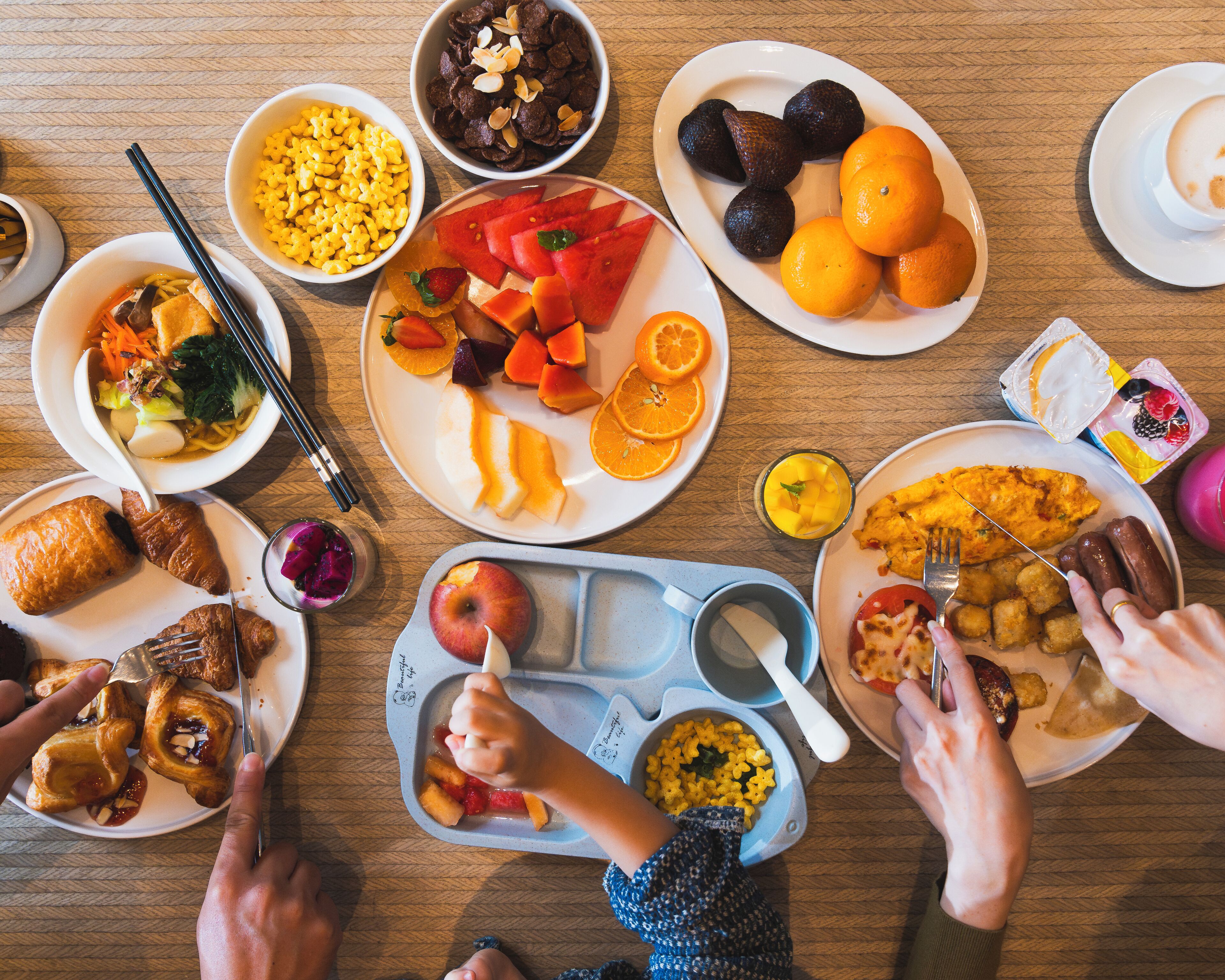 Ein Tisch mit verschiedenen Speisen, darunter Obst, Gemüse und eine Mahlzeit mit Tater Tots.