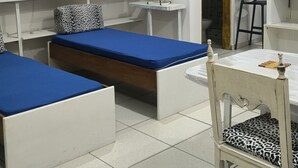 Une pièce comprenant un lit, une chaise, une table et un ventilateur.