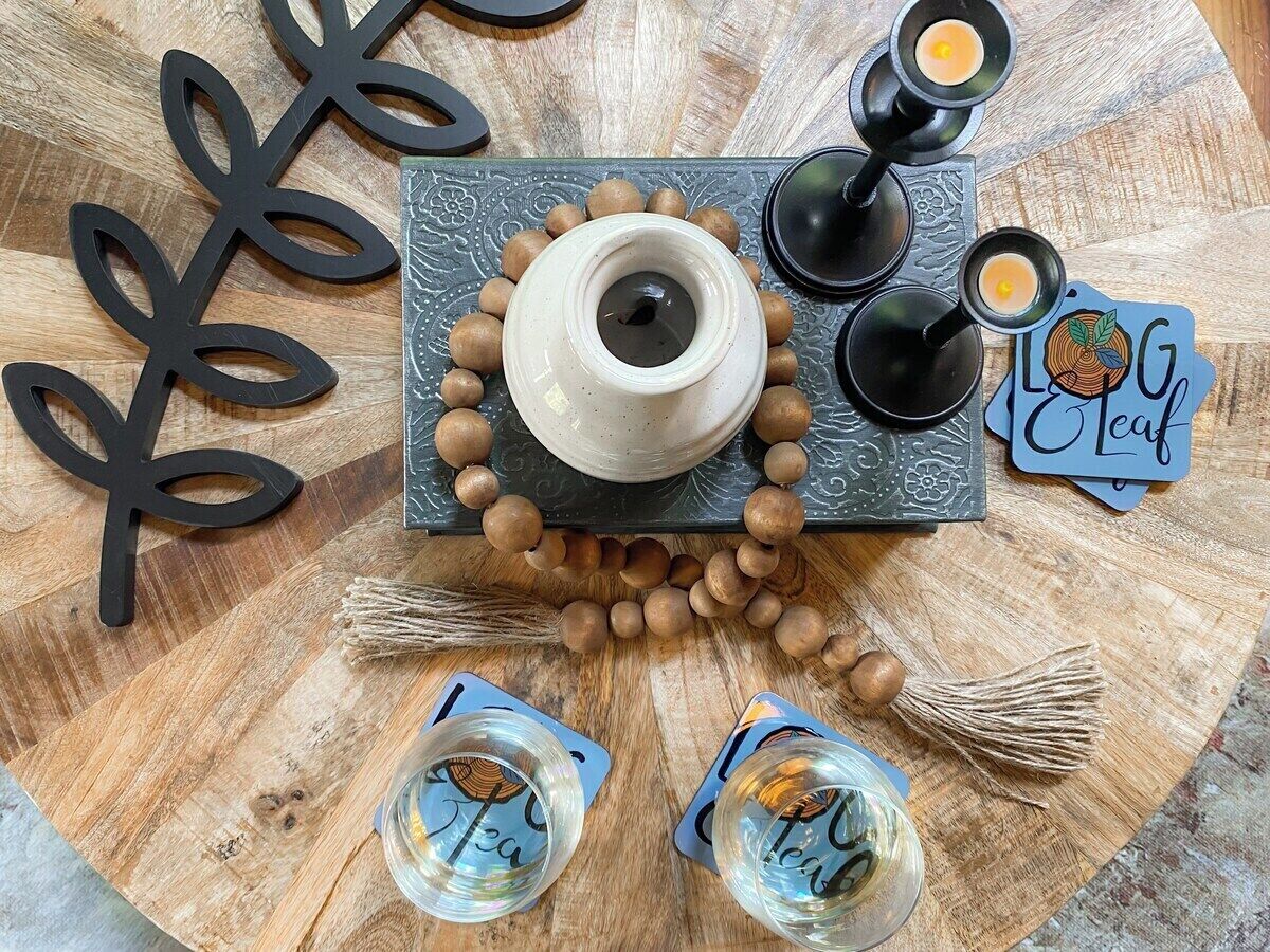 A wooden table with a decorative centerpiece, including a teapot, cups, and a card.