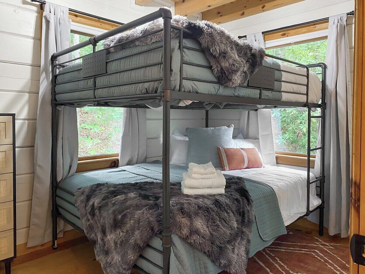 Un lit superposé avec une couverture moelleuse, une serviette pliée et des oreillers.