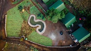 An aerial view of a property with a green-roofed building, a winding water feature, and a fenced area with trees. - Bosque de Perlillas (Ocoyoacac)