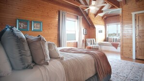 Un dormitorio acogedor con una cama grande, vigas de madera en el techo y vista al área de estar.