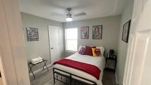 A bedroom with a bed, a ceiling fan, a window, and artwork on the walls. - Right by AT&T, Rangers stadium (Arlington)