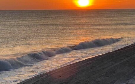 A sunset over the ocean with waves crashing onto the shore.