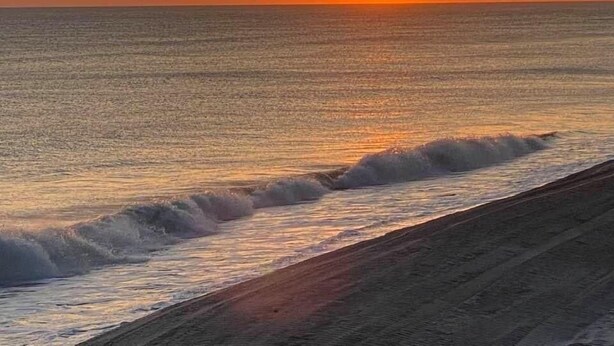 A sunset over the ocean with waves crashing onto the shore. - Cute waterfront bungalow, tons of amenities, a small gated fishing community! (Dauphin Island)