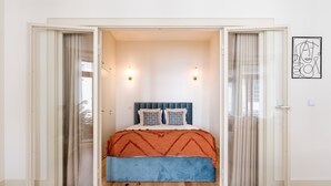 Une chambre à coucher avec un lit, deux appliques murales, un tableau et une porte coulissante.