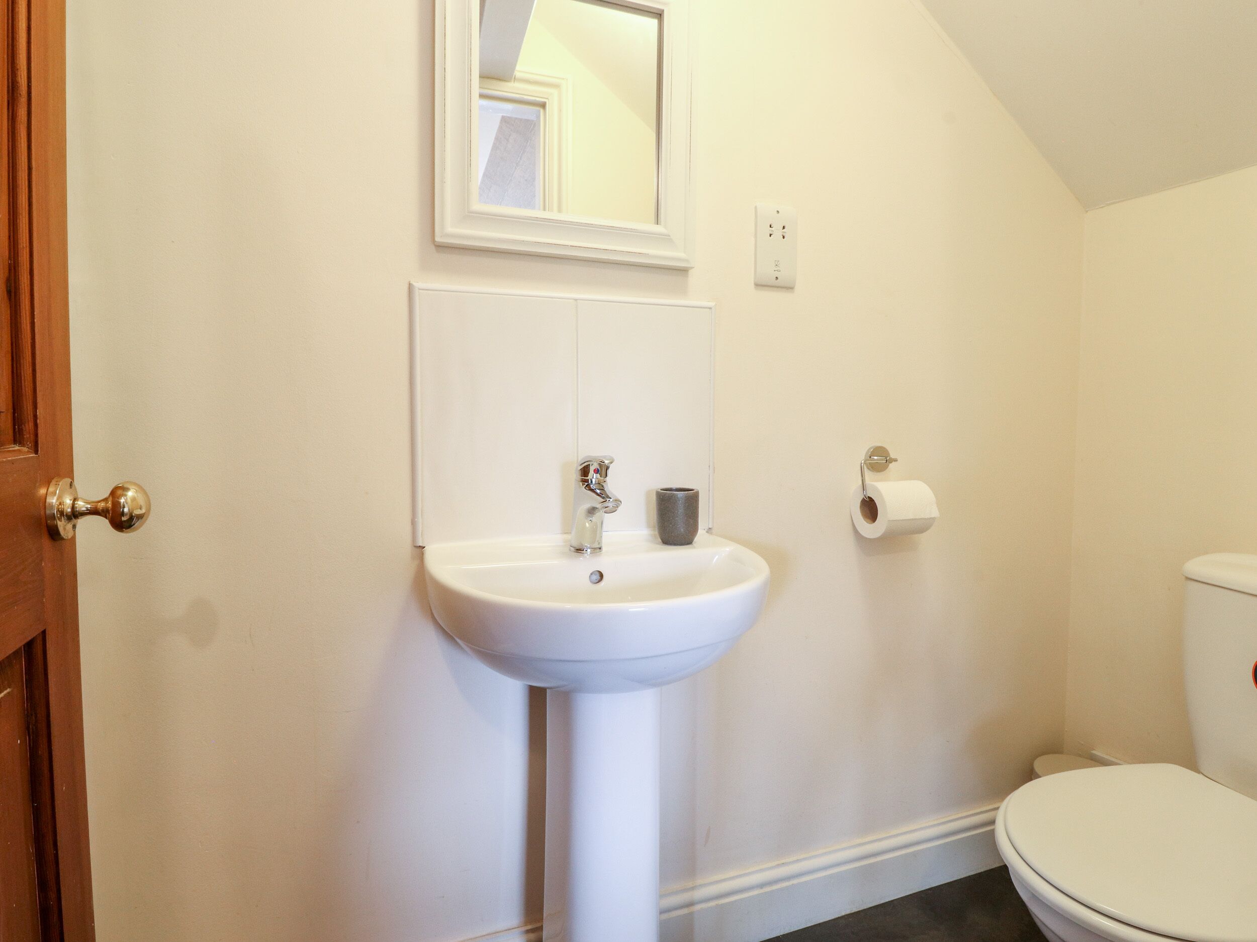 Un bagno con lavandino bianco, uno specchio, un water e una porta.