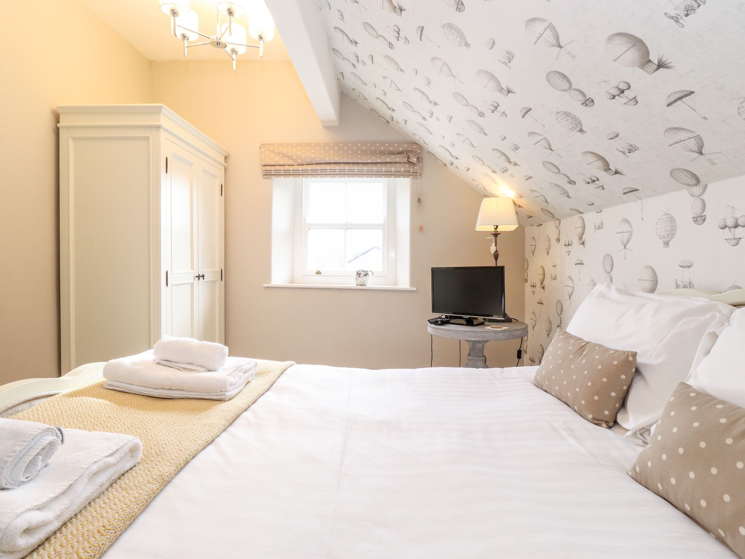 Une chambre à coucher avec un lit, un téléviseur posé sur une petite table, une fenêtre et une armoire.