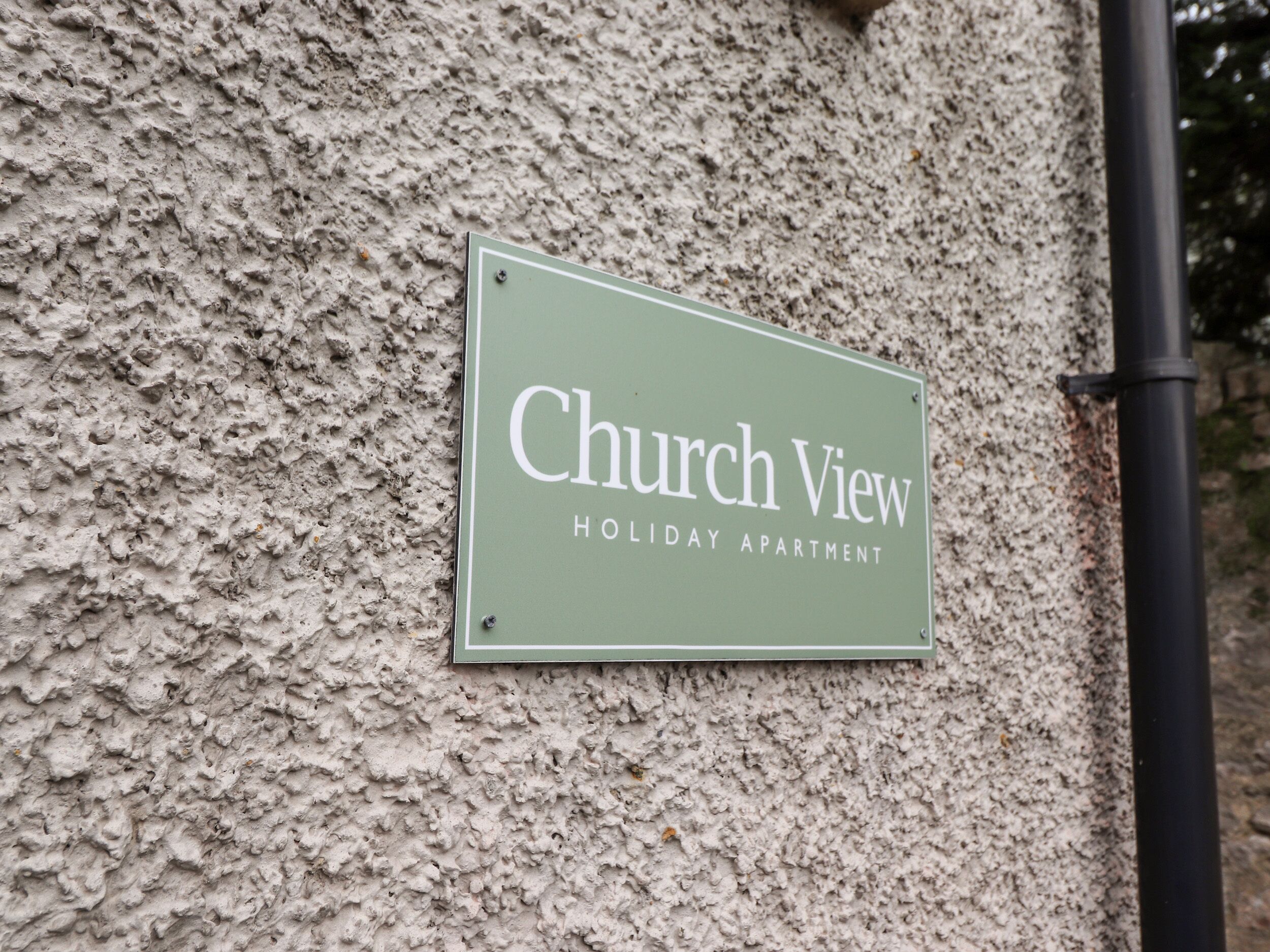 A sign on a textured wall that reads "Church View Holiday Apartment."