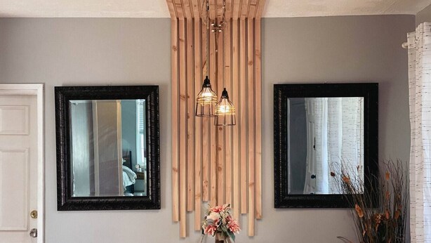Un coin repas avec une table en bois dressée pour quatre personnes, flanquée de deux miroirs et d’un luminaire suspendu.