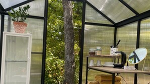 A greenhouse with a glass door, a white cabinet, a wooden desk, and a mirror. - Cedar Springs Greenhouse (Decorah)