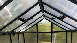 A greenhouse with a bed, a small table, and a chair. - Cedar Springs Greenhouse (Decorah)