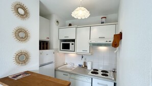 A compact kitchen with white cabinets, a microwave, a sink, and a stove.