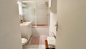 A bathroom with a shower, sink, toilet, and a towel rack.