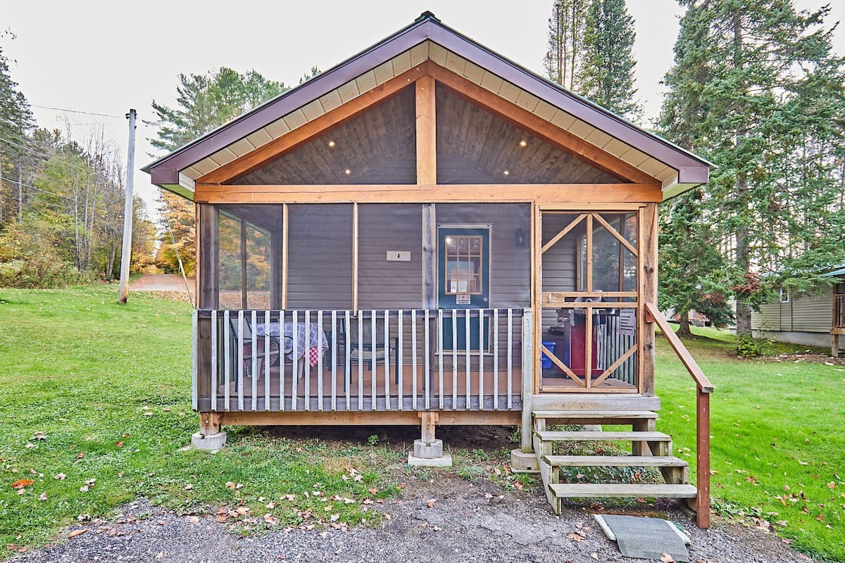 Une cabane avec une façade en bois, une véranda et un petit escalier menant à l’entrée.
