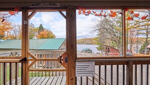 A wooden deck with a view of a lake and buildings in the background. - Dayspring Cottages (Armour)