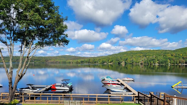 A lakeside view with boats docked, a wooden deck, and a fire pit area. - Dayspring Cottages (Armour)