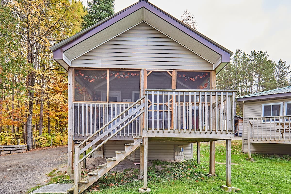 Une cabane avec un porche à l’avant, un escalier et une terrasse.
