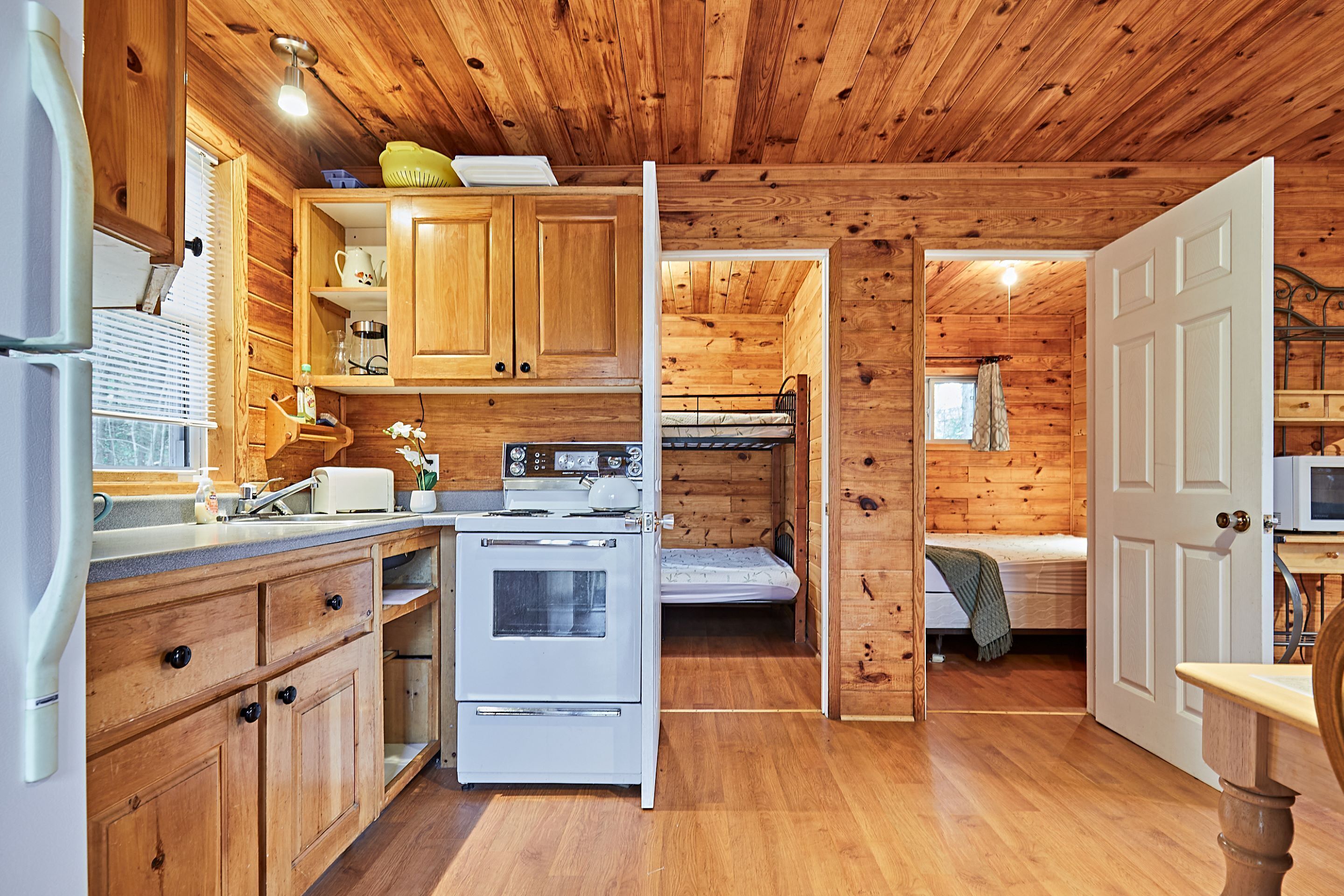 Una cocina tipo cabaña compacta con armarios de madera, estufa blanca y un lavamanos.