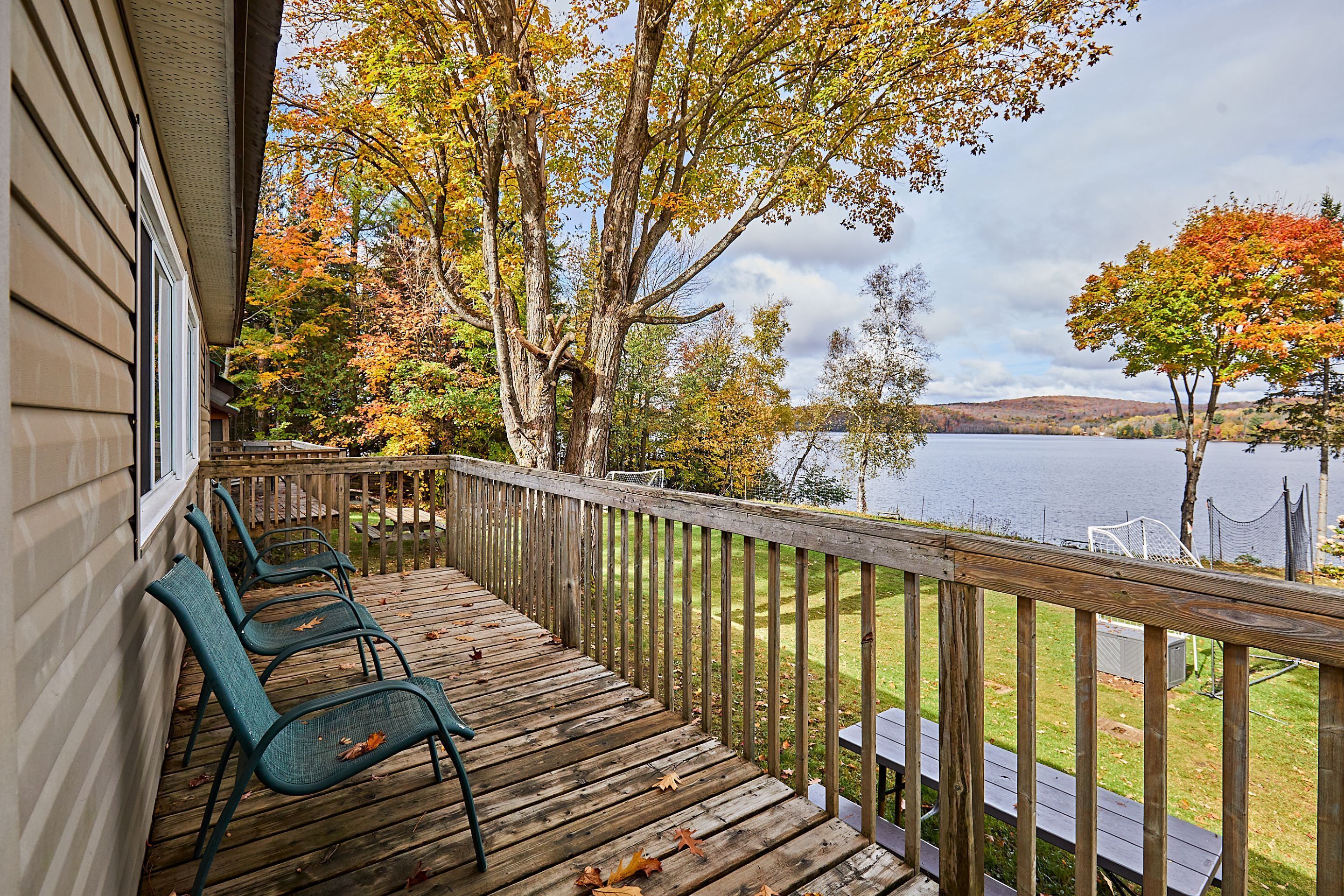 Una terraza de madera con sillas y vistas a un lago.