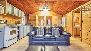 A log cabin interior with a leather sofa, wooden cabinets, and a kitchenette. - Dayspring Cottages (Armour)