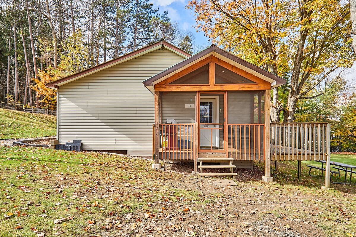 Une petite cabane avec une véranda en bois et une table de pique-nique.