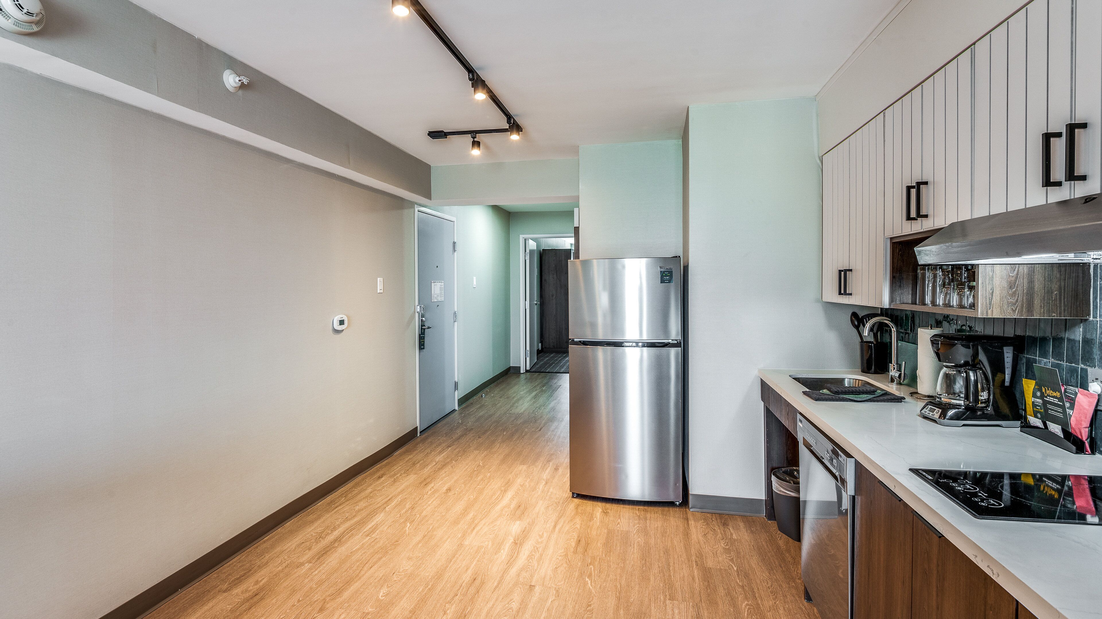 Una cocina moderna con un refrigerador de acero inoxidable, una cafetera y armarios de madera.
